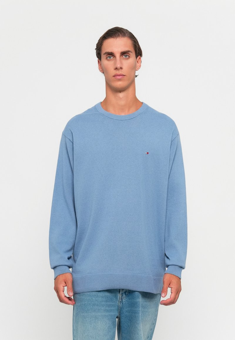 Maglione azzurro chiaro con collo rotondo, maniche lunghe e orlo a coste. Presenta un piccolo logo sul petto. Realizzato in tessuto morbido.