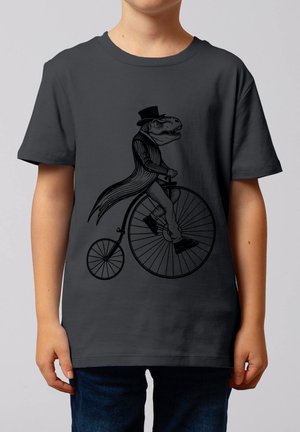 Kind draagt een donker T-shirt met een afbeelding van een dinosaurus in een hoge hoed en jas die op een hoge bifiets rijdt.