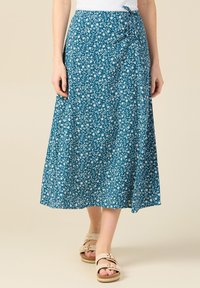 Kukkaprinttisellä, teal-värisellä kankaan ympäröivällä hameella, A-linjaisella leikkauksella, nilkkapituisella, jossa on sivusolmuke ja lievää rakennetta.