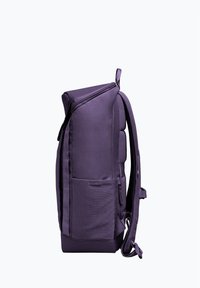 Un sac à dos violet avec une surface texturée, un dos rembourré, des bretelles réglables et une poche latérale. Il présente une fermeture éclair et un design épuré.