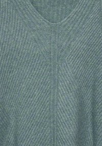 Grön ribbad tröja med V-ringning, texturerat tyg i varierande nyanser och diagonala mönsterdetaljer över hela.