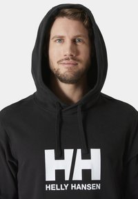 Sudadera negra con un gran logo blanco "HH" y texto "HELLY HANSEN", que cuenta con una capucha con cordón y una textura suave.
