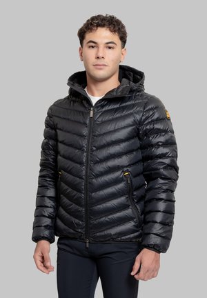 Giacca imbottita nera con cappuccio, caratterizzata da un motivo trapuntato a zigzag, chiusura con cerniera, due tasche frontali e piccolo dettaglio logo giallo.