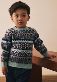 Stickad tröja med rund halsringning i mjuk ull, med ett flerfärgat geometriskt mönster i marinblått, grönt, rost och vitt.