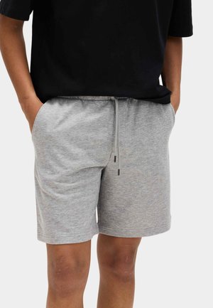 Grå bomuldsshorts med elastik i taljen og snøre, med sidelommer og en afslappet pasform. Bruges med en sort T-shirt.