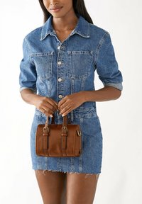 Sac à main en cuir brun avec de courtes poignées, comportant des accents en métal doré. Le sac a une forme rectangulaire et une texture lisse.