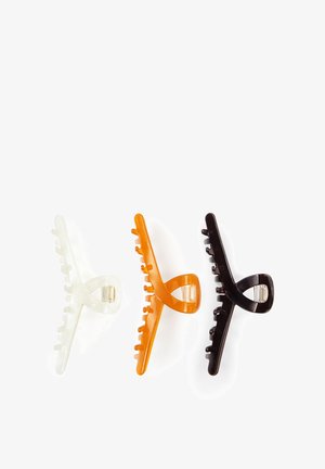 Tre plast hårklemmer i transparent hvid, orange og mørkebrun, arrangeret side om side på en hvid baggrund.