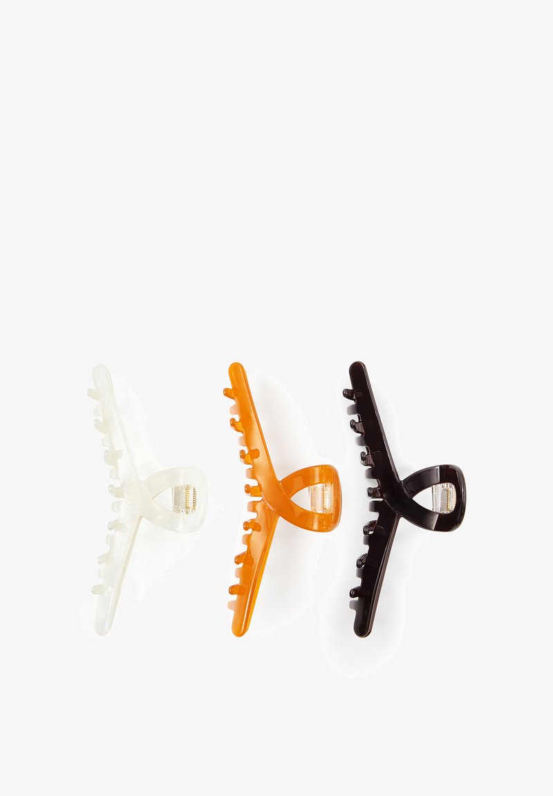 Three plastic hair claw clips in translucent white, orange, and dark brown, arranged side by side on a white background.