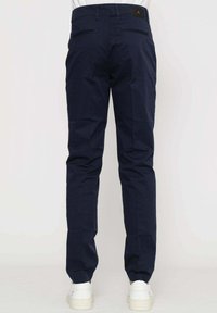 Pantaloni blu navy in slim fit, realizzati in cotone, con due tasche posteriori e una etichetta con il marchio in vita. Tessuto testurizzato.