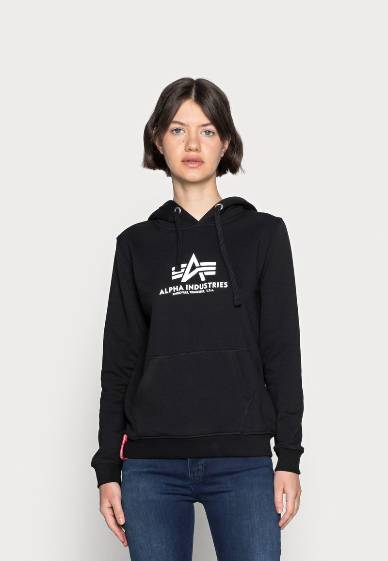 Fekete kapucnis pulóver pamut keverékből, elülső zsebbel, húzózsinórral ellátott kapucnival és fehér "Alpha Industries" logóval. Rugalmas mandzsettákkal és heméllyel rendelkezik.