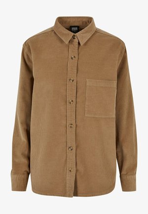 Camisa de pana marrón con botones en la parte delantera, cuello puntiagudo, mangas largas y un bolsillo en el pecho. Presenta una sutil textura vertical y botones marrones.