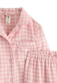 Lyserøde flannel pyjamas med et ternet mønster, der har en notch krave, en lomme på skjorten og en elastisk talje på bukserne.