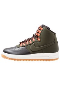 High-top sneakers in black and olive green, featuring orange eyelets, textured leather, and a white rubber sole with a gum outsole.
