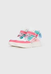 Ténis altos com painéis em rosa, branco e azul esverdeado; decorados com contas e fitas; superfícies texturizadas; solas brancas grossas.