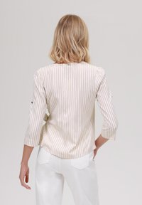 Stripet, lys beige og hvit bluse med trekvart lange ermer og rund halslinje, med en avslappet passform og subtil teksturert stoff.