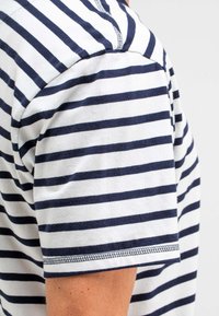 Gestreiftes Baumwoll-T-Shirt mit horizontalen Marine- und weißen Streifen, rundem Halsausschnitt und genähten Säumen an den Ärmeln.