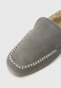 Grey suede loafer with white stitched detailing around the toe and a soft, light brown inner lining, shown from a top corner angle.