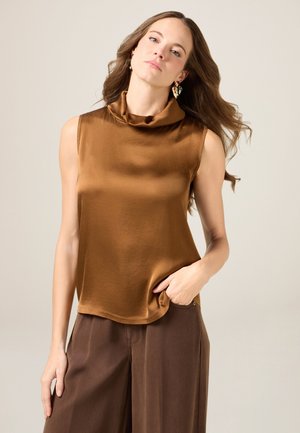 Haut sans manches en bronze avec un décolleté drapé, fabriqué à partir d'un tissu lisse ; associé à un pantalon large marron, présentant un détail de poche.