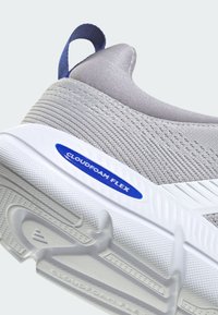 Šedá športová obuv s textúrovaným zvrškom, bielou gumovou podrážkou a modrým detailom "CLOUDFOAM FLEX". Obsahuje pútko na päte.
