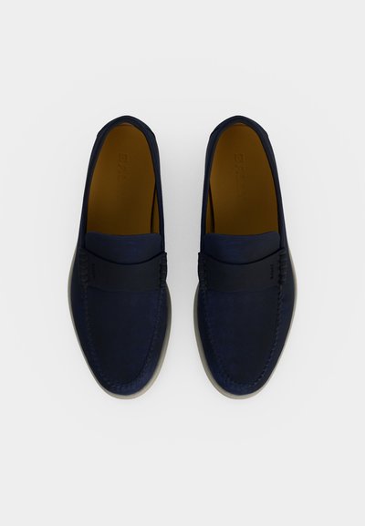 Ζευγάρι σκούρα μπλε σουέντ μοκασίνια με μαύρη λεπτομέρεια λουριού και ταμπά εσωτερικό, σε λευκό φόντο, από ψηλά.