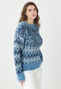 Strickpullover in Blautönen mit einem Muster aus Rauten und geometrischen Designs, mit einem gerippten Saum und Bündchen. Weiche Textur.