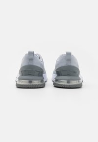 Scarpe da ginnastica grigie in rete con supporto in plastica sul tallone, ammortizzazione d'aria trasparente e suola in gomma texturizzata. Linguetta sul retro per una facile calzata.