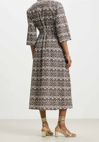 Brun och vit mönstrad klänning med trekvartsärmar, cinchad midja och midi-längd, som matchas med guldiga remsandaler med blockklack.