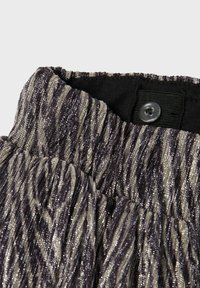 Tessuto strutturato nero e argento con un design plissettato, dotato di chiusura a bottone e vita elastica. Elementi lucidi distribuiti uniformemente.