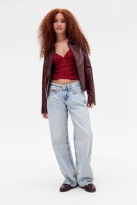 Giacca in pelle bordeaux, top corto in pizzo rosso, jeans a gamba larga blu chiaro e scarpe scure. Presenta trame intricate e un fit rilassato.