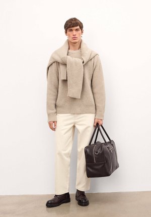 Suéter de punto beige con una bufanda caída sobre los hombros, pantalones de pierna ancha color crema y bolso de cuero marrón con dobles asas y cremalleras.