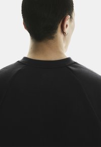 Zwarte sweatshirt met een ronde halslijn en raglanmouwen, met een gladde textuur en eenvoudig ontwerp, gezien vanuit de achterkant.