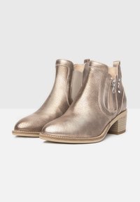 Bottines en bronze métallisé avec texture perforée, bout rond, petit talon empilé et détail de zip latéral pour un enfilage facile.