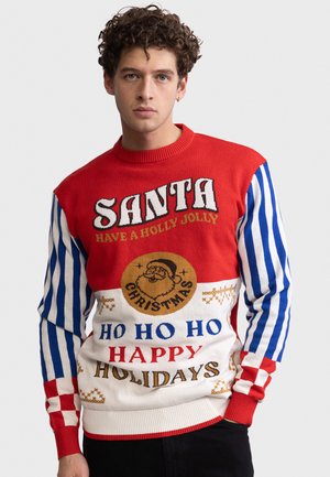 Homme portant un pull festif à rayures rouges, blanches et bleues, avec un motif du Père Noël et des phrases de Noël telles que "Santa", "Ho Ho Ho", "Happy Holidays".