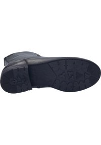Bota de cuero negro con suela de goma texturizada. La suela presenta un patrón de dibujo multidireccional para mayor tracción. Cremallera en el costado para el cierre.