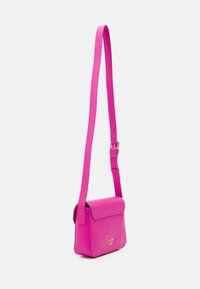 Borsa a tracolla in pelle rosa con patta e manico regolabile. Caratterizzata da dettaglio del logo dorato e texture liscia per un design moderno.