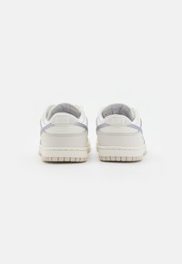 Baskets Nike, vue arrière, en cuir blanc avec des accents bleu clair. Comprend un col rembourré et une semelle en caoutchouc avec une texture antidérapante.