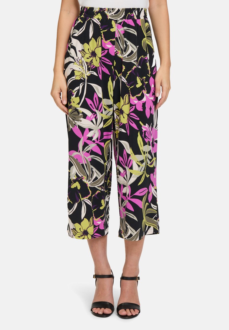 Spodnie w kwiatowy print z czarnym tłem, ozdobione żywymi różowymi, zielonymi i beżowymi kwiatami. Elastyczny pas i krótki, szeroki krój nogawek.