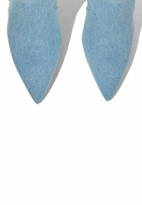 Jasnoniebieskie jeansowe buty na szpilkach z gładką teksturą i detalami szwów. Projekt charakteryzuje się elegancką sylwetką.