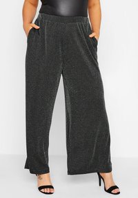 Svarta vida byxor i mjukt, texturerat tyg med en subtil lyster. Har elastisk midja och sidfickor för extra bekvämlighet.