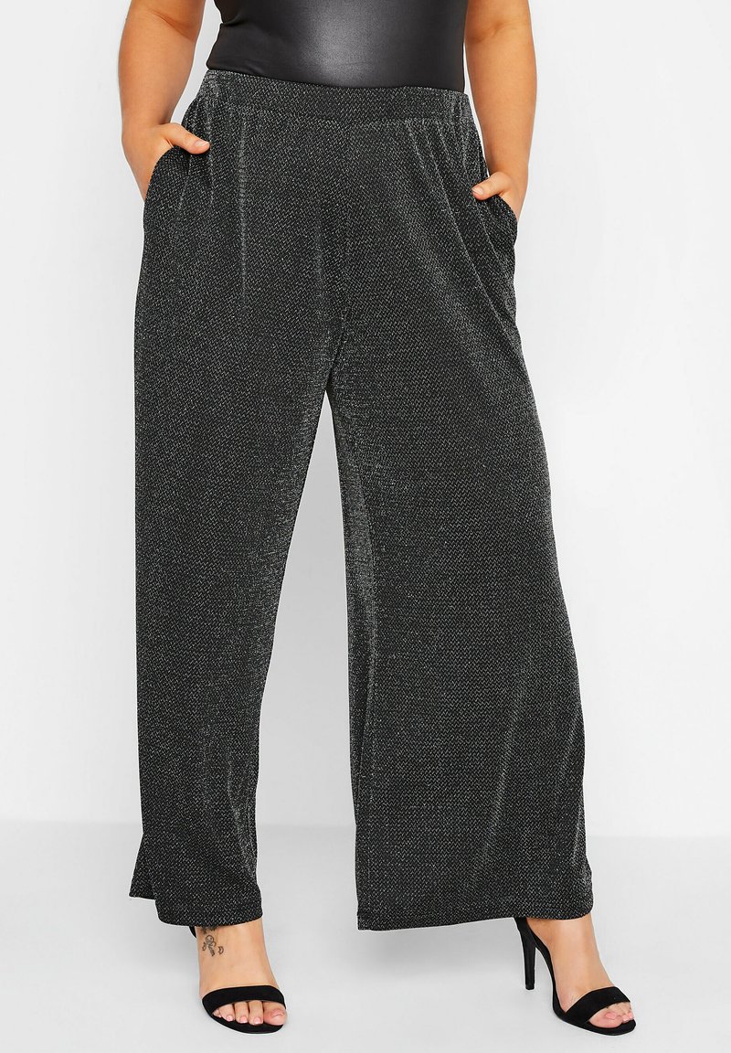 Svarta vida byxor i mjukt, texturerat tyg med en subtil lyster. Har elastisk midja och sidfickor för extra bekvämlighet.