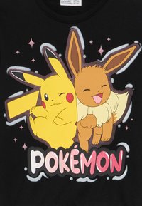 Il tessuto nero presenta una grafica colorata di Pikachu ed Eevee, entrambi con forme distintive, che stanno insieme sotto il testo "Pokémon".