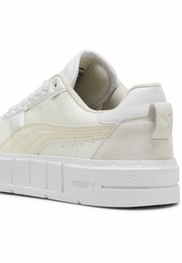 Vita sneakers med en slät läderovandel och mockadetaljer, med en tjock vit sula och subtil branding nära hälen.