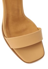 Sandale beige à bout ouvert avec une large bride à l'avant et un détail de semelle de forme carrée.