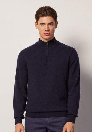 Dunkelblaues Zip-Neck-Pullover mit langen Ärmeln, aus weichem Material gefertigt. Mit einem gerippten Kragen und Bündchen ausgestattet, die einen angenehmen Sitz bieten.