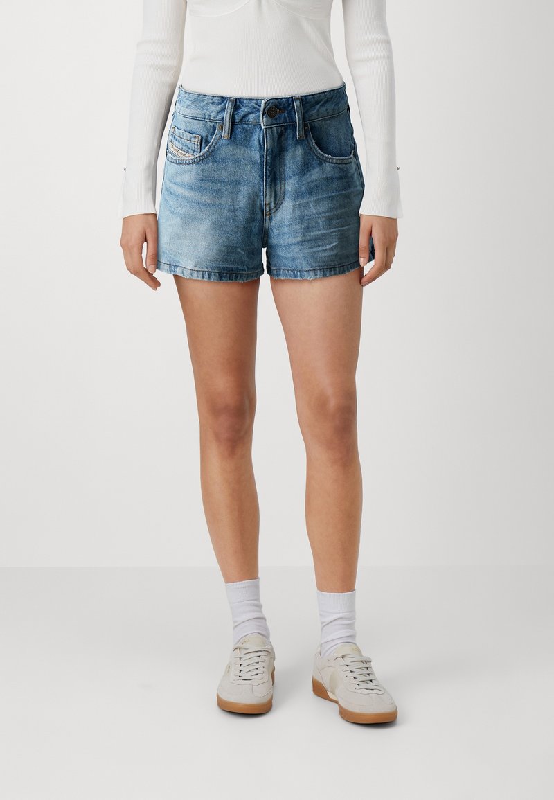 Shorts in denim azzurro chiaro, con orlo sfilacciato, design a cinque tasche e chiusura con bottone. Abbinati a calze bianche alla caviglia e sneakers chiare.