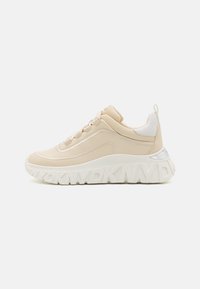 Beige sneakers med glatt lær og tekstiloverdel, hvit teksturert såle, reflekterende detaljer og logo-detaljer på sålens side.