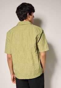 Korte mouwen overhemd in lichtgroene, gestructureerde stof, met een subtiel reliëfspiraalpatroon en een klassiek kraagontwerp.