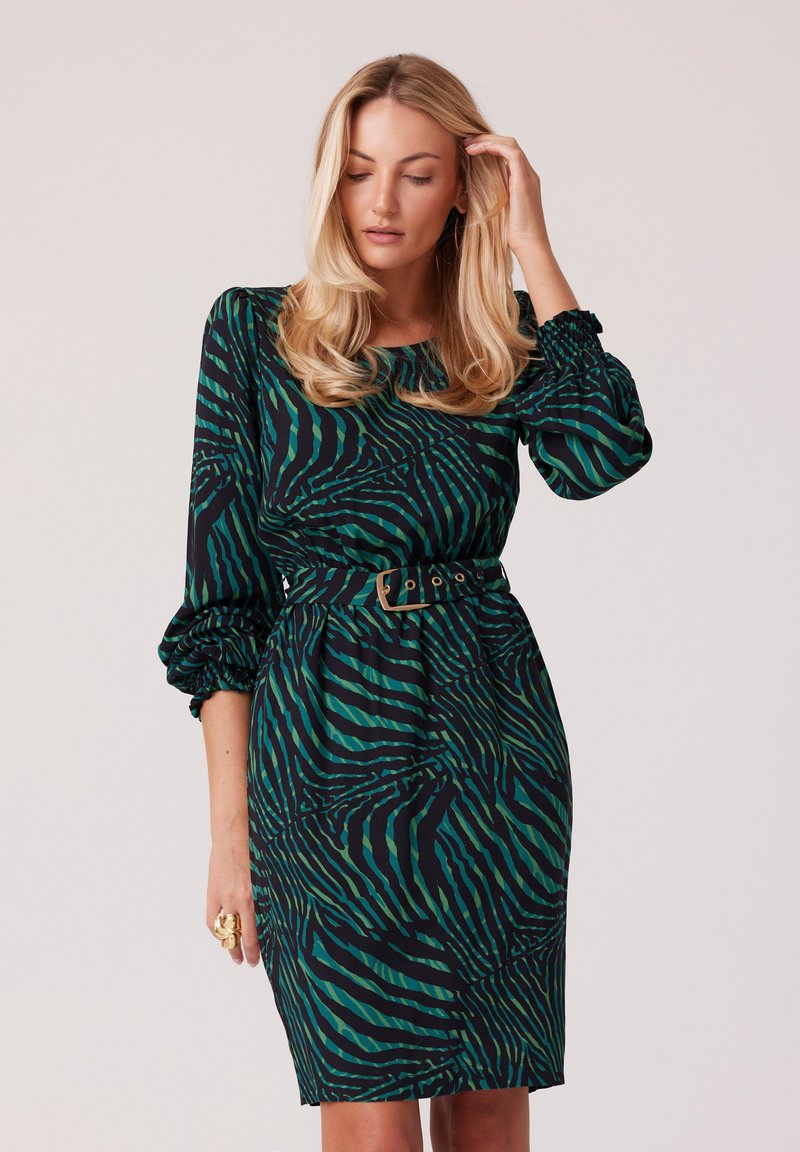 Zielono-czarna sukienka w paski zebry z długimi bufkami, zgromadzonym dekoltem oraz dopasowaną talią podkreśloną paskiem.