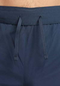 Bañador de marine con cintura ajustable, fabricado en una tela suave y ligera, con un diseño simple y sin patrones ni acentos visibles.