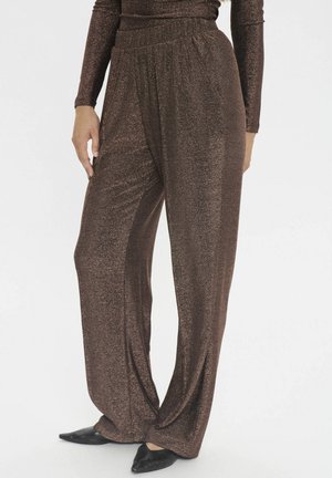 Braune, glitzernde weite Hosen aus einem weichen Material mit einem elastischen Bund. Kombiniert mit schwarzen spitzen Ballerinas.